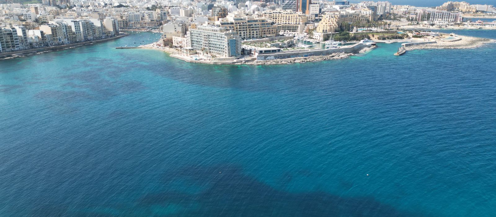A stunning aerial view of Sliema's coastline, showcasing its modern architecture and vibrant blue Mediterranean Sea.