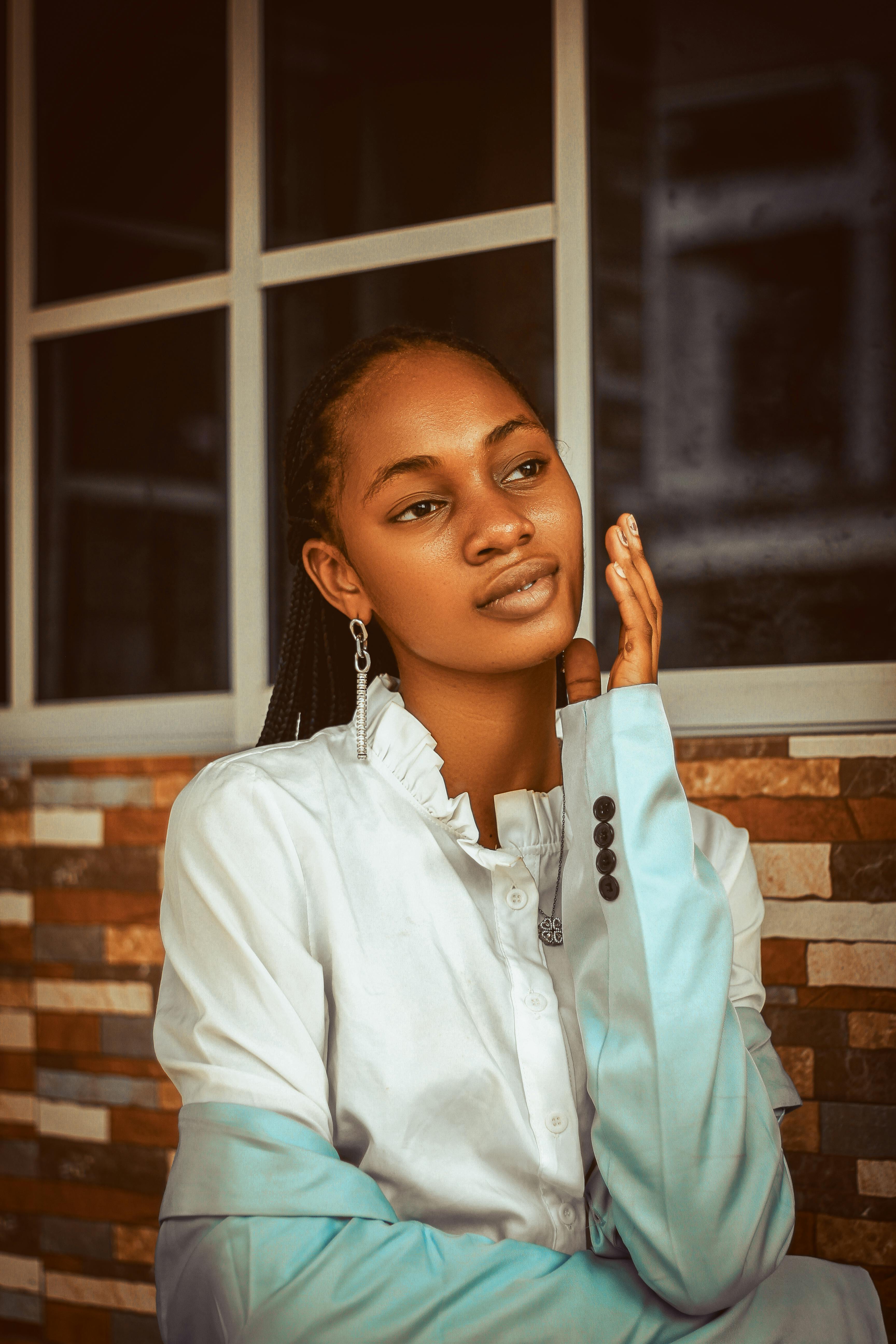 Stylish portrait of a young woman in white shirt, posing indoors with a thoughtful expression.