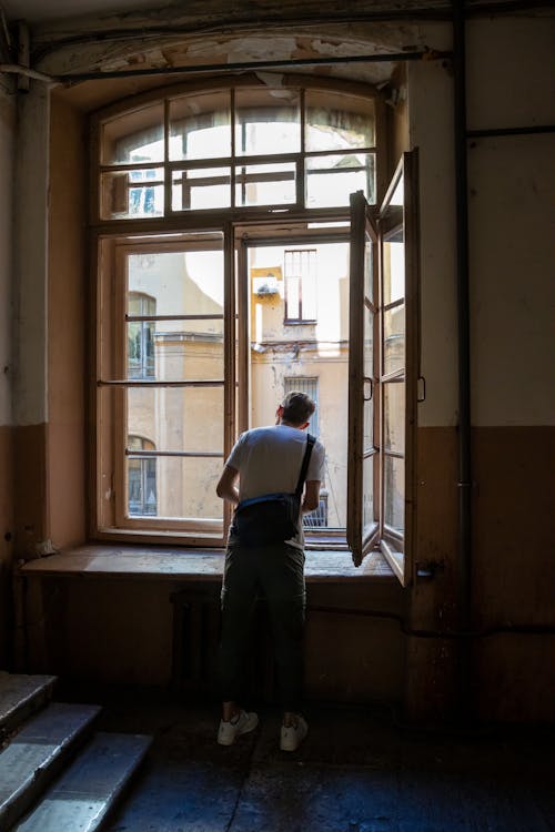 A Man Looking Out the Window in a Tenement House