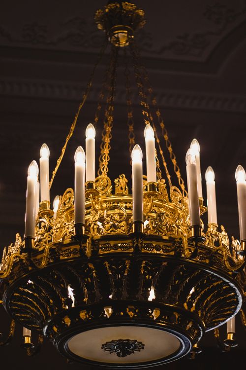 Free Elegant golden chandelier with candles casting a warm glow in a Russian palace. Stock Photo