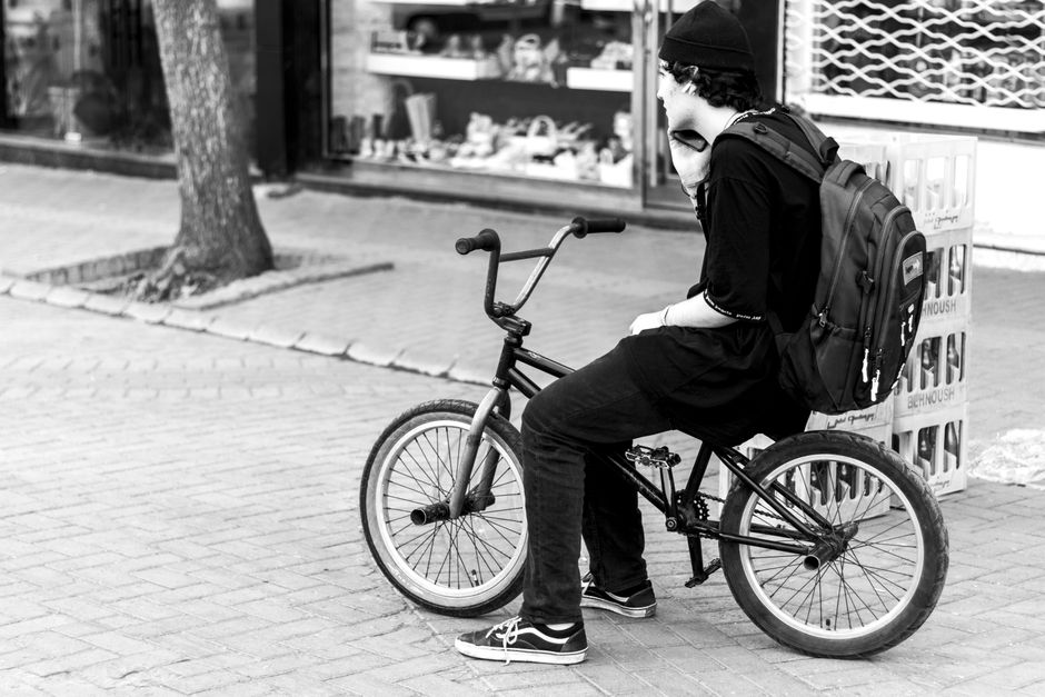 Teenager with backpack sitting on a BMX bike in the urban streets of Tabriz, Iran.