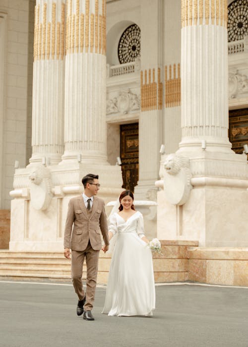Bride and Groom Walking in front of a Classical Building 