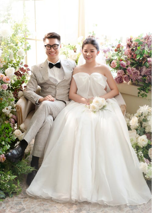 Bride and Groom Sitting on a Couch among Flower Decorations 