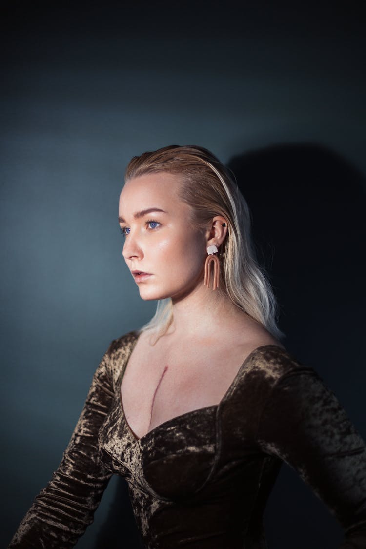 Portrait Of A Blond Woman With Heart Surgery Scar On Decolette, Against Indigo Background