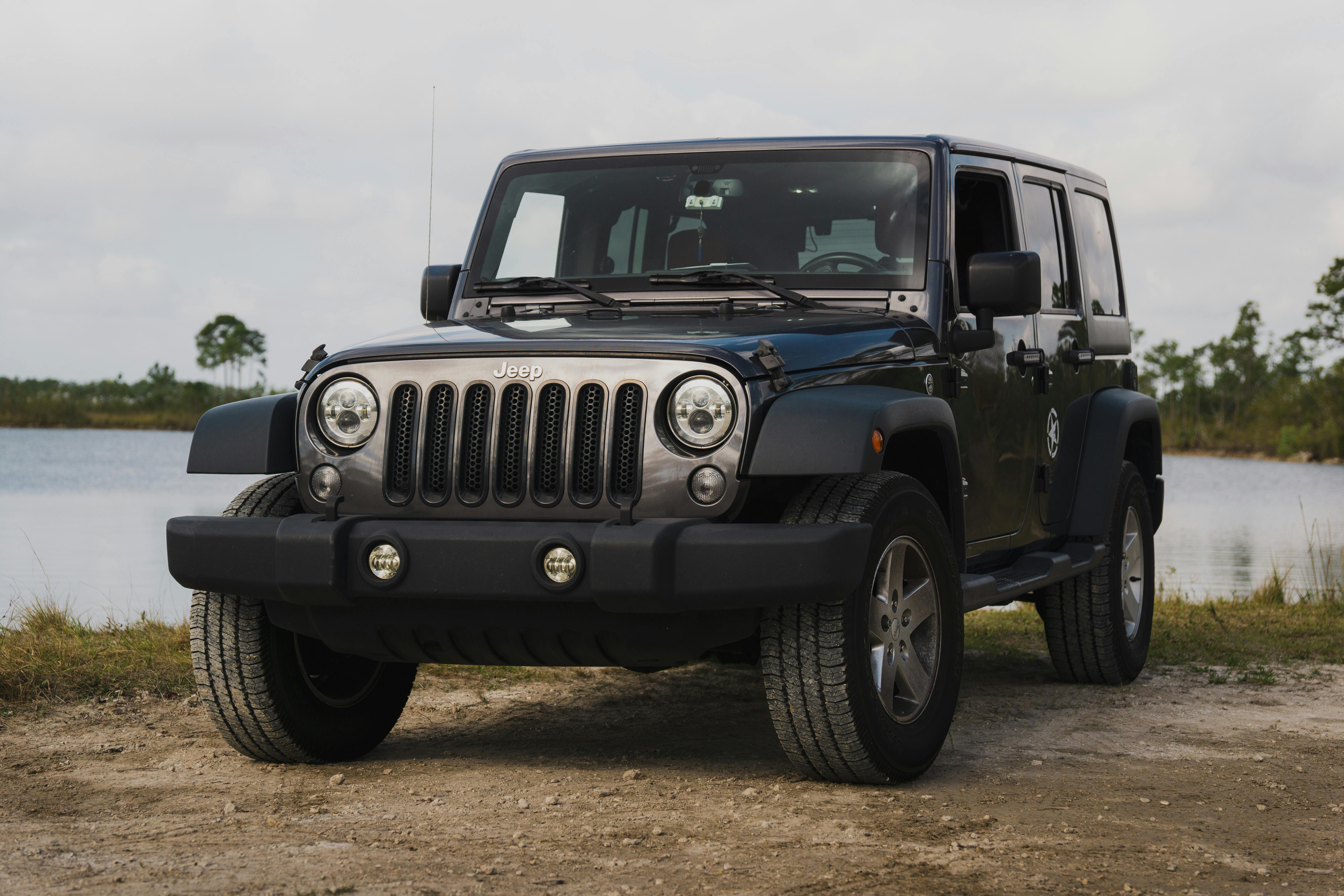 A black Jeep Wrangler parked by a serene lake in rural Florida, showcasing adventure.