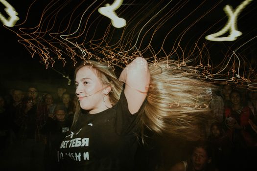Woman dancing energetically under vibrant lights in a lively club setting.