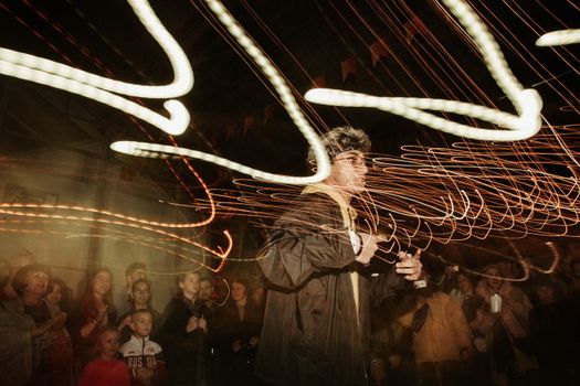Energetic scene of a man performing with light trails at a lively nightclub party.