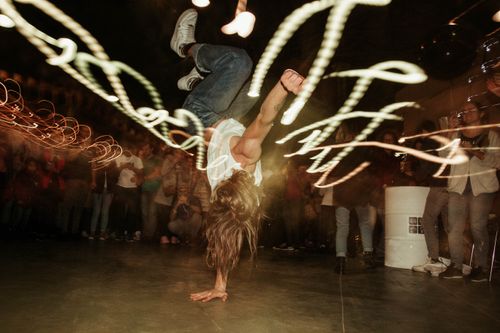 Free Energetic breakdancer performing amidst vibrant party setting with lights. Stock Photo