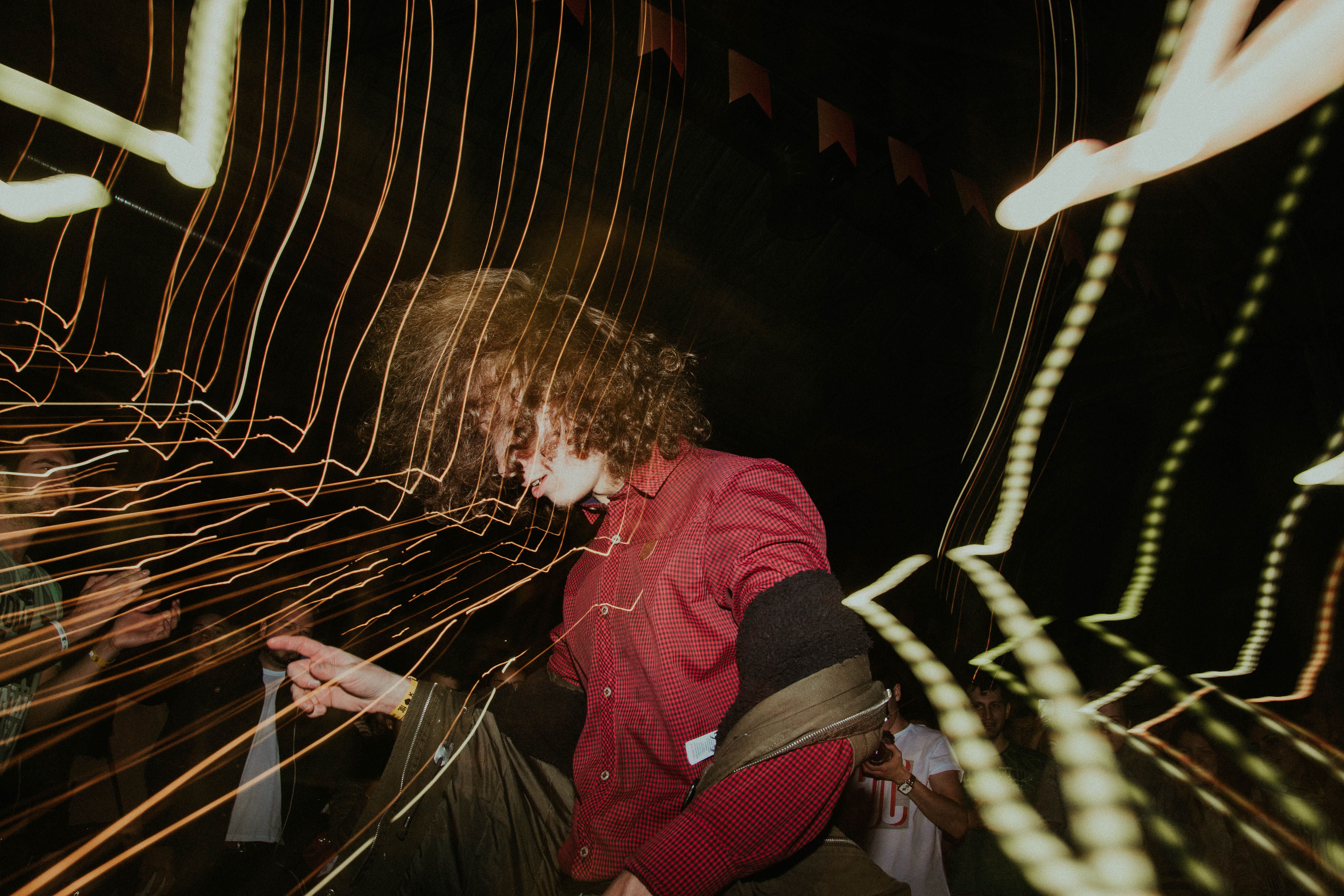 Vibrant night party featuring a man in a red shirt with dynamic light trails captured in long exposure.