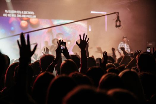 A lively indoor concert with a crowd of people raising hands and enjoying the music.