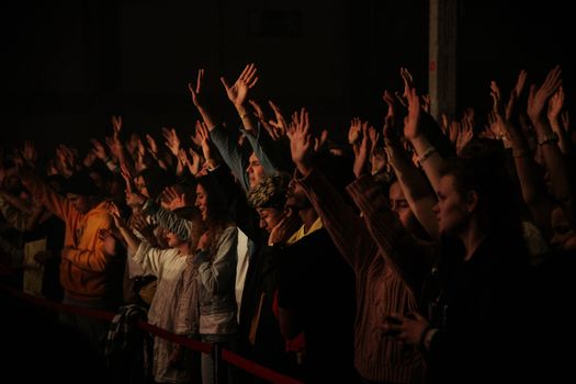 A lively audience with raised arms enjoying a nighttime music festival.