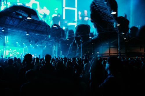 Free Energetic crowd enjoying a live concert indoors with vibrant lighting and double exposure effect. Stock Photo