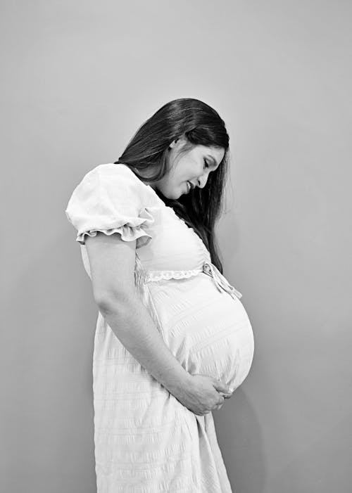 Бесплатное стоковое фото с беременная, вертикальный выстрел, глядя вниз
