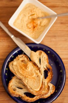 Delicious homemade toast served with creamy hummus spread on a rustic wooden surface.