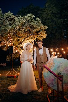 Bride and groom at an outdoor wedding under illuminated trees and lights.