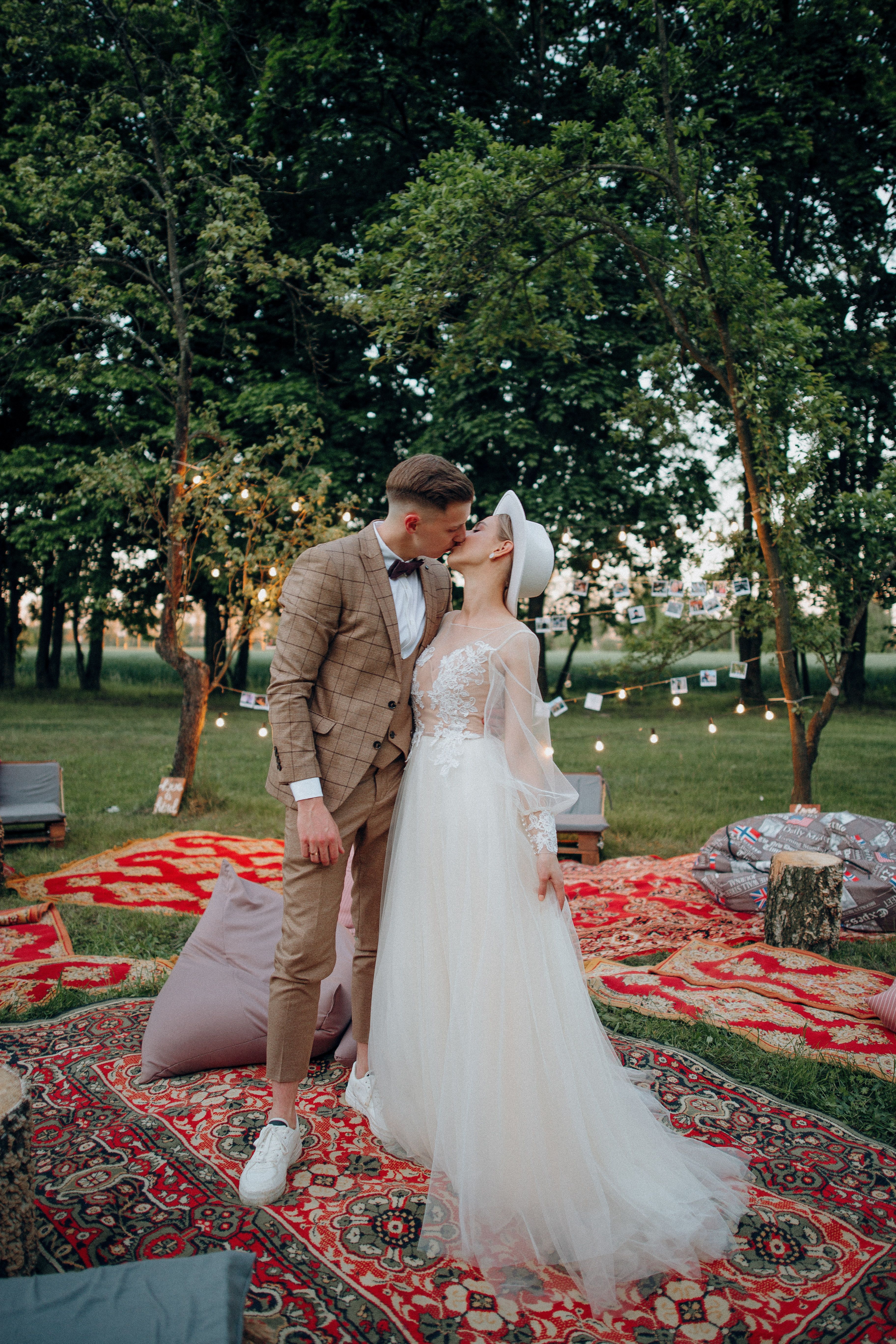 A bride and groom sharing a romantic kiss outdoors on a summer day.