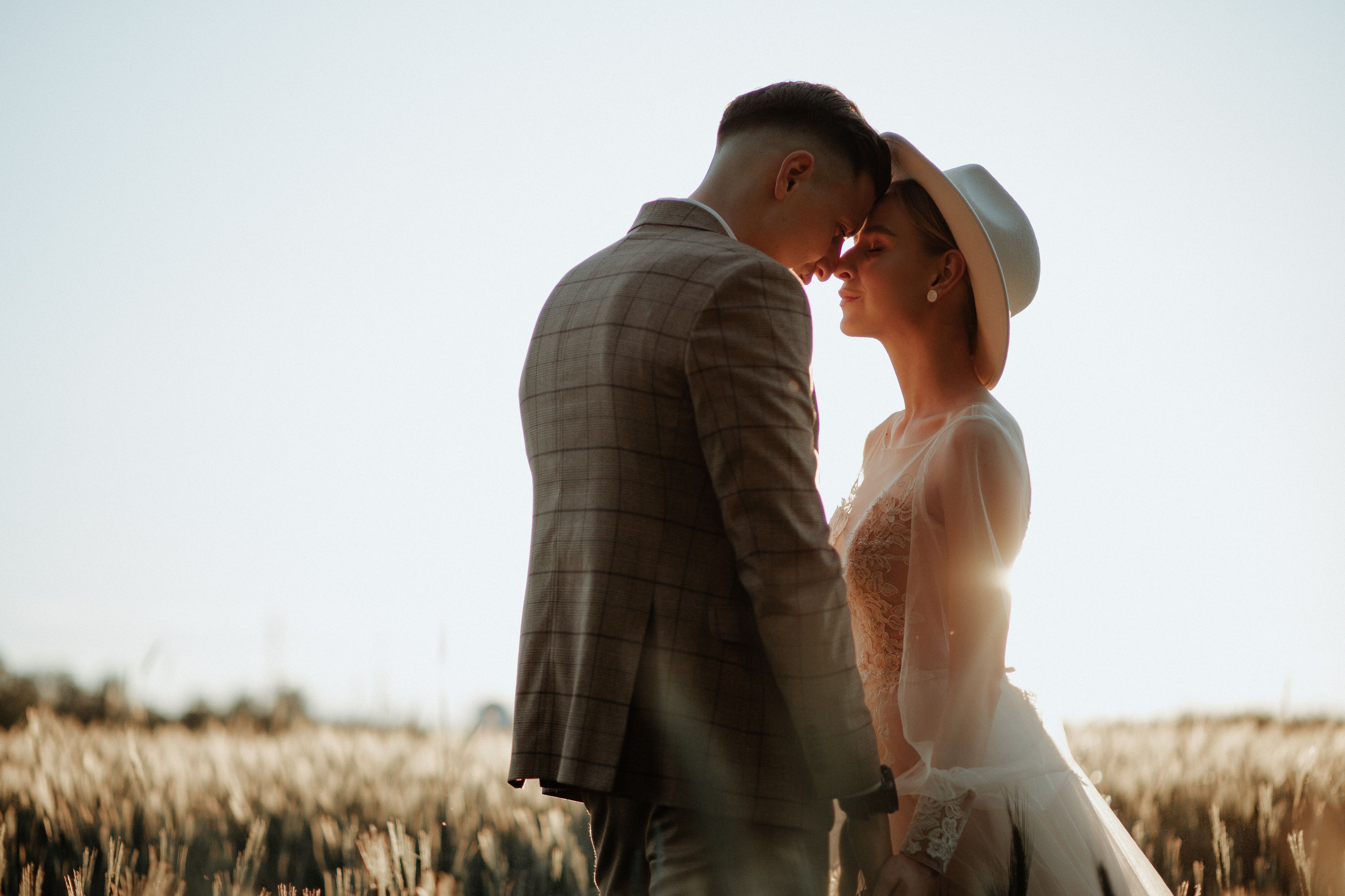 Couple in a field at sunset in wedding attire