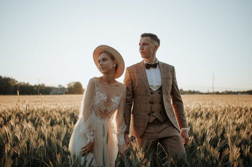 Newlyweds in Wedding Dress and Suit Posing on Field