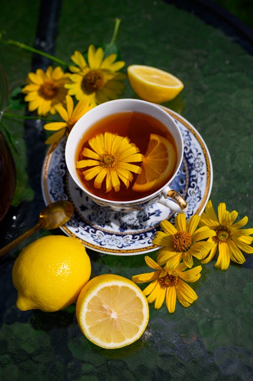 Flower in teas and lemons on the table and a mug of tea with lemon. cup with flowers and lemon. Tea drinking concept. Summer tea