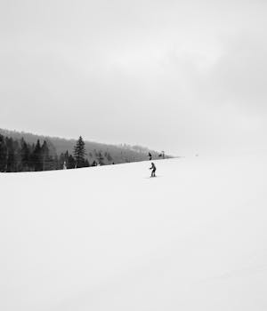 A skier glides down a snowy slope in Kolasin, Montenegro, under cloudy skies.