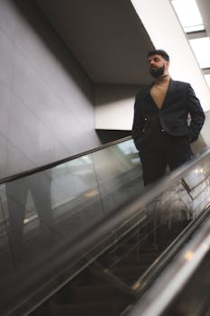 Stylish man in a suit on an escalator indoors, exuding modern elegance.