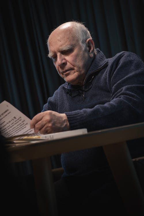 Elderly Man Sitting by Table and Reading