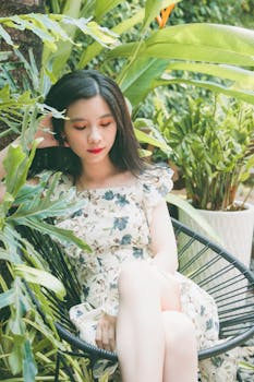 一位身着花卉连衣裙的优雅女士，在郁郁葱葱的绿色植物间舒适地放松身心