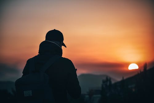 Free Man Wearing Baseball Cap and Backpack at Golden Hour Stock Photo