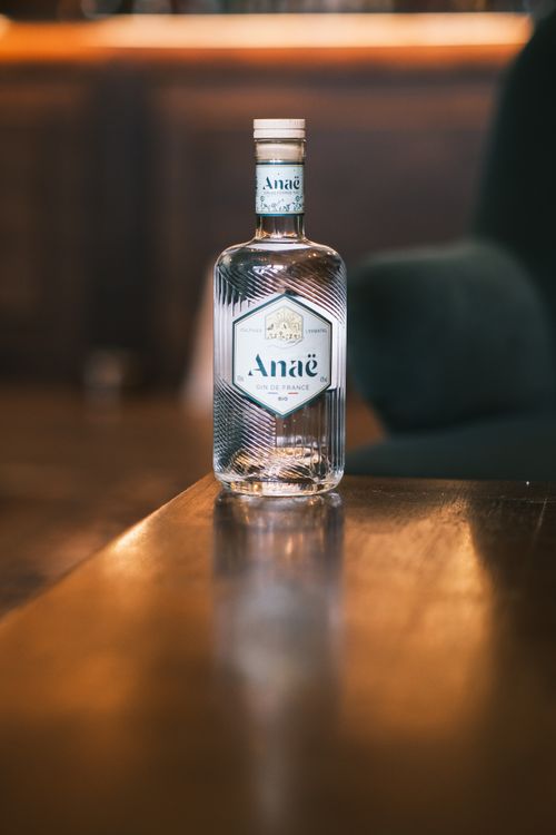 Free Close-up of an Anae gin bottle placed on a polished wooden table in a cozy indoor setting. Stock Photo