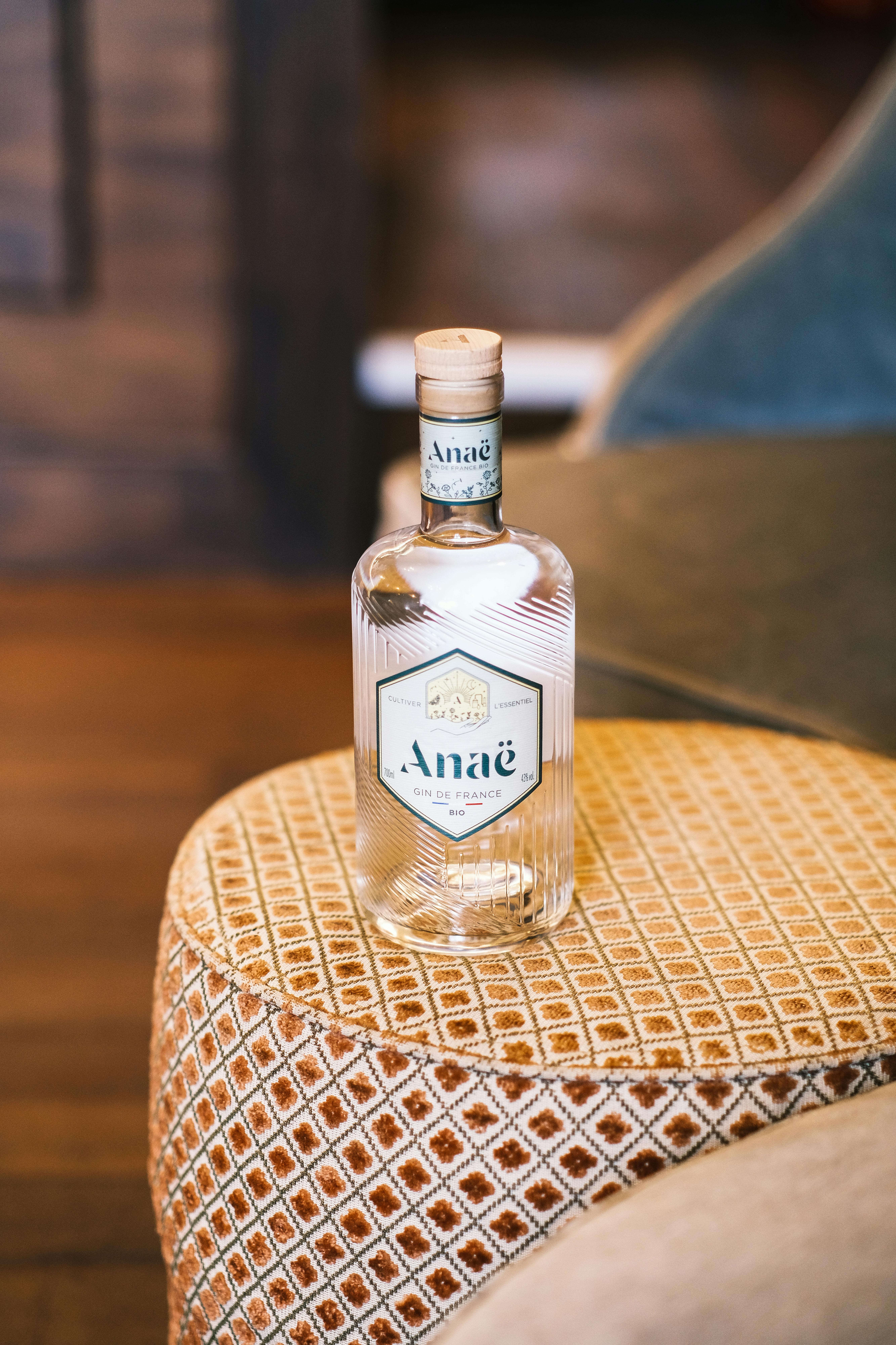 Close-up of an Anaë bottle elegantly placed on a vintage patterned cushion in an indoor setting.