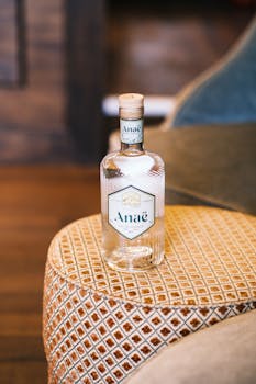 Close-up of an Anaë bottle elegantly placed on a vintage patterned cushion in an indoor setting.