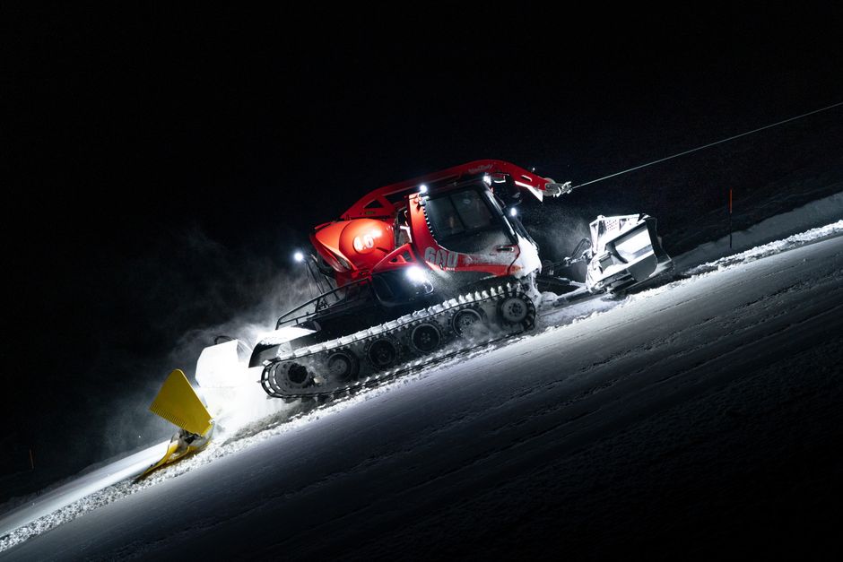 A snow groomer operates at night on a snowy slope in Zermatt, Switzerland.