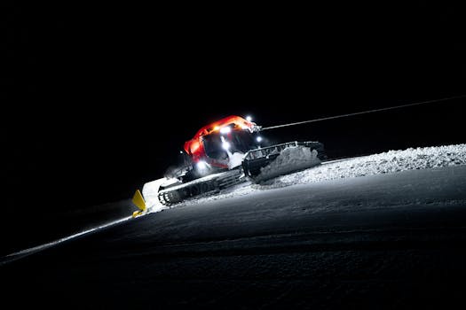 Snow groomer smoothing ski slopes in Zermatt, Switzerland at night.