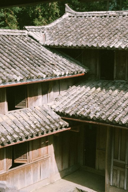 A traditional wooden building with tiled roofs sunlit, showcasing classic Asian architectural style.