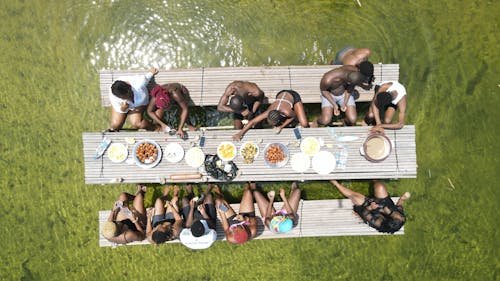 People Sitting at Wooden Table Having Picnic in Water