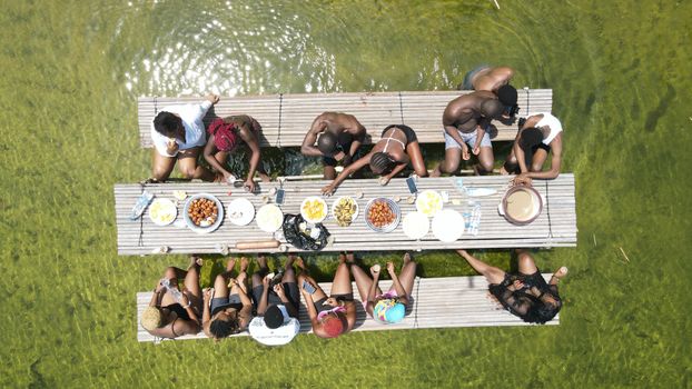 A group of people enjoying a picnic on a floating wooden deck during summer.