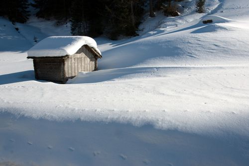 Free Serene snowy scene with a wooden shed amidst untouched winter fields. Stock Photo