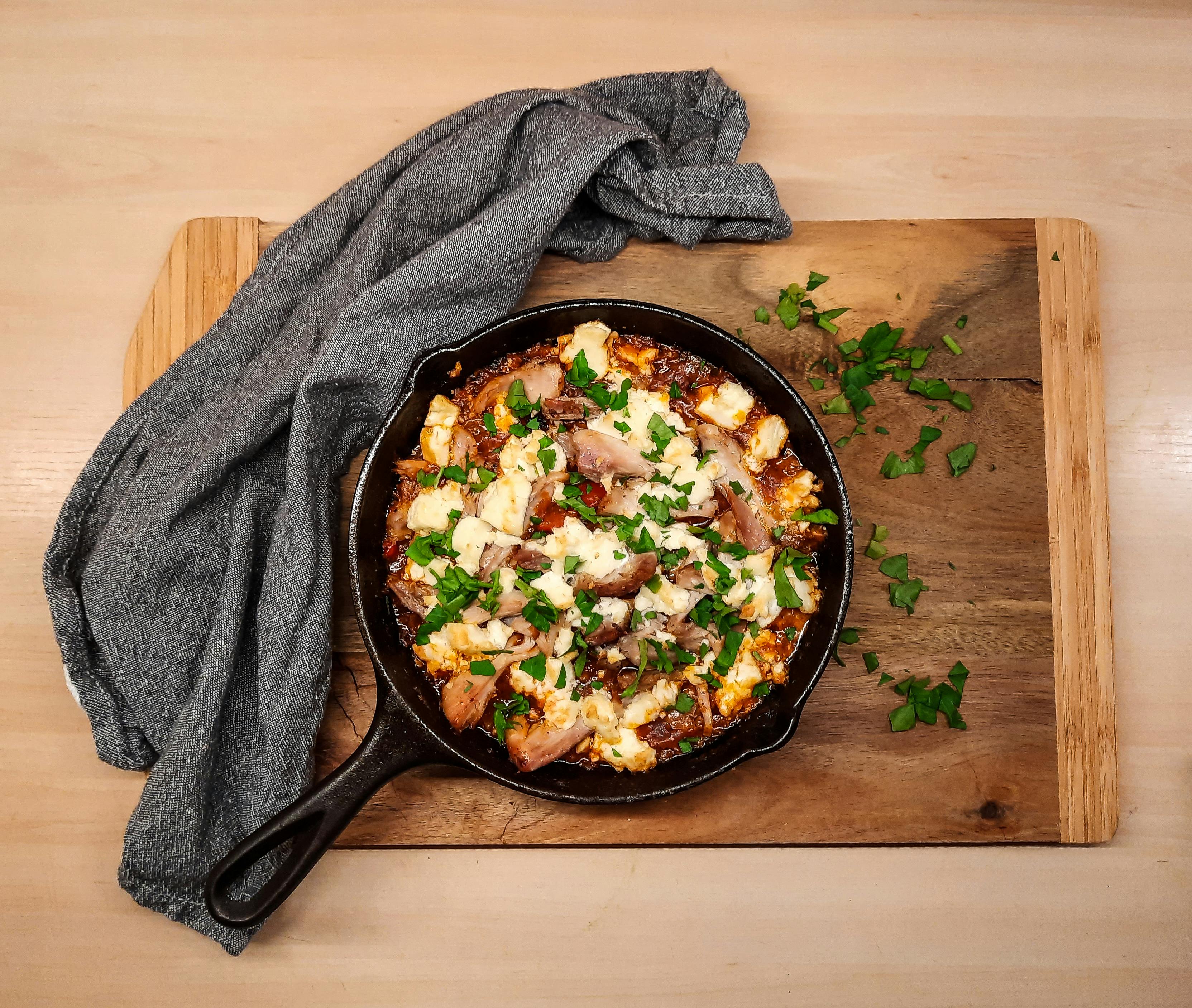 Bubbling bouyourdi with melted feta cheese and charred peppers in a cast iron skillet, served with crusty bread
