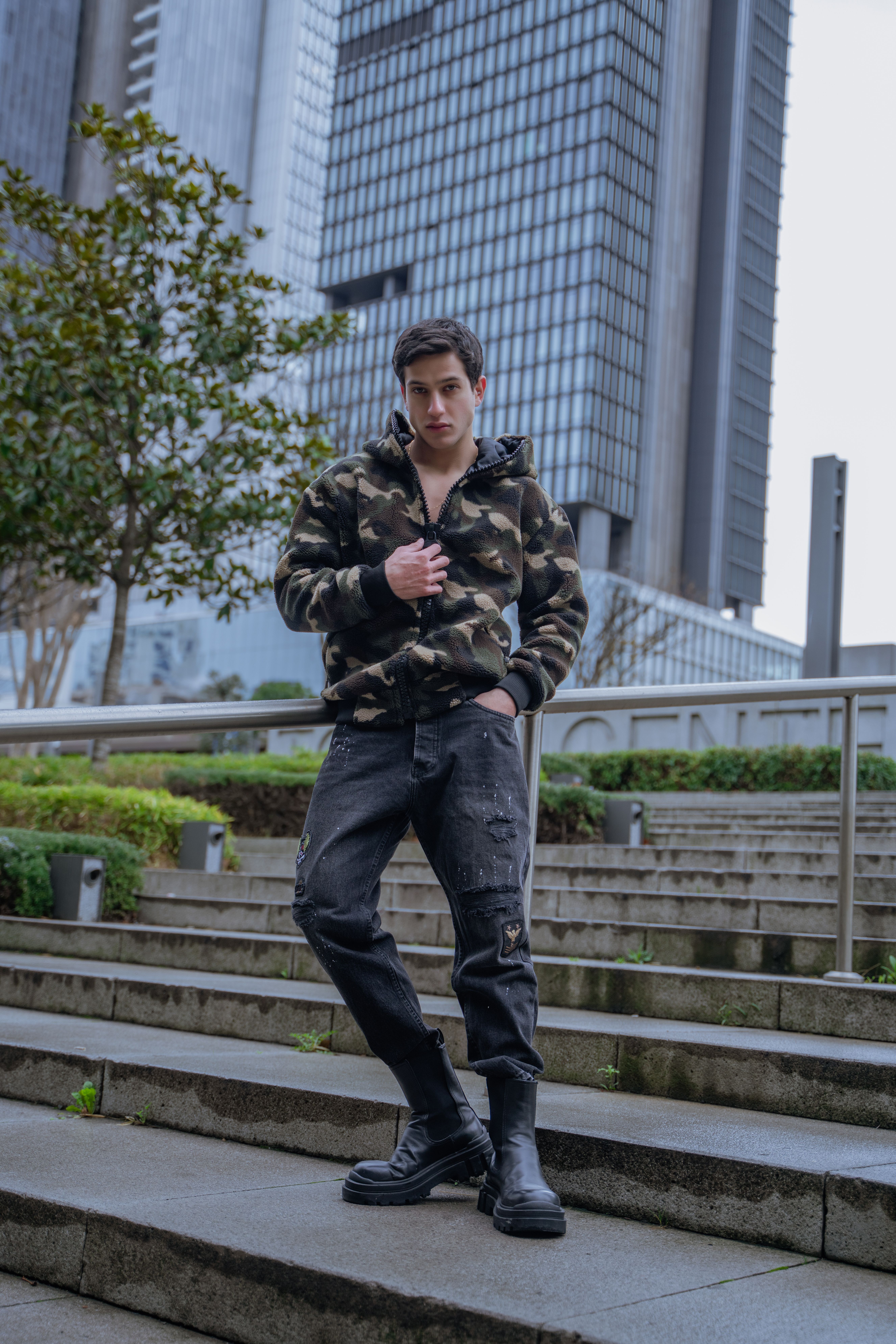 Stylish male model in camouflage jacket photographed in İstanbul cityscape.