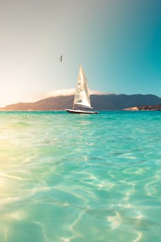 一艘帆船滑过碧绿的海洋，在晴朗的天空下，非常适合宁静的旅行和度假场景