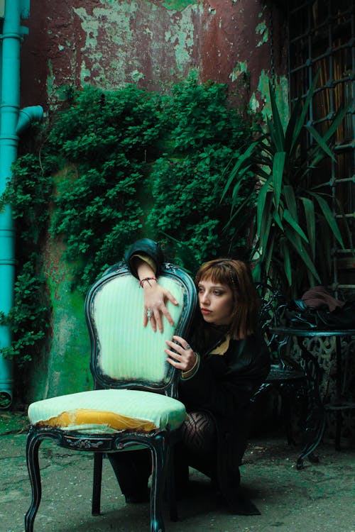 Green Toned Photo of a Woman Posing with a Vintage Chair and Plants in Background