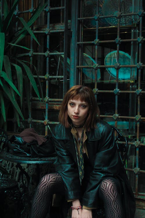 Green Toned Photo of a Woman Posing by a Metal Gate