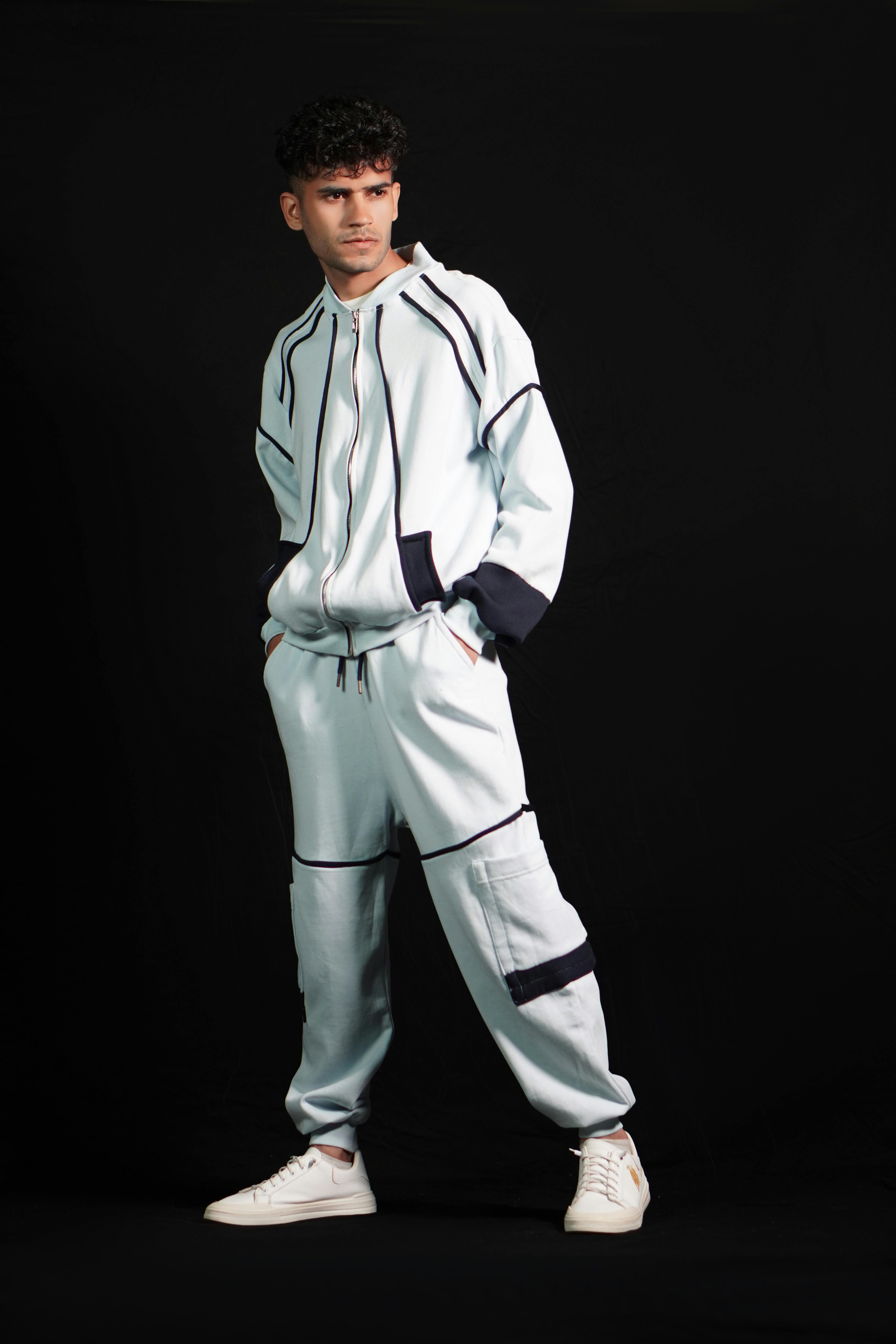 Free Portrait of a man in contemporary sportswear, standing confidently against a black background. Stock Photo