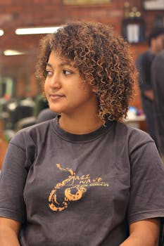 Young woman with curly hair looking aside indoors, relaxed pose.