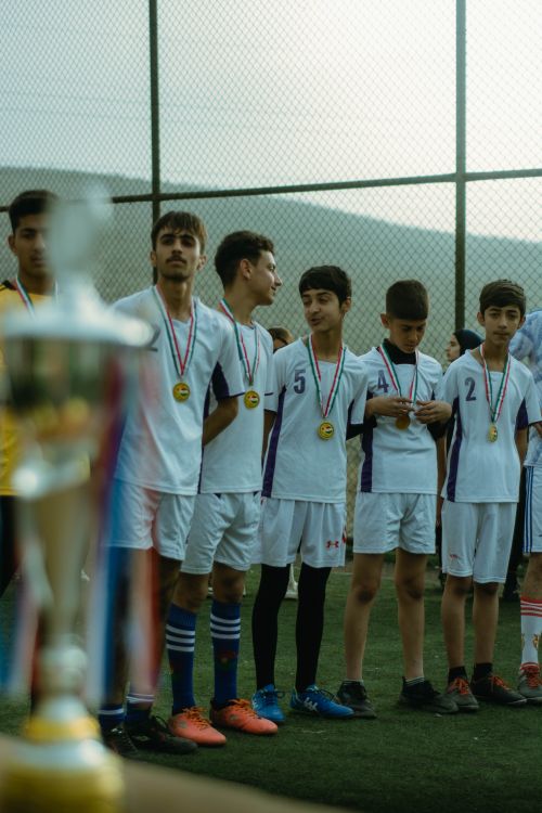 Free Teenage soccer team in Erbil celebrating victory with medals on outdoor field. Stock Photo