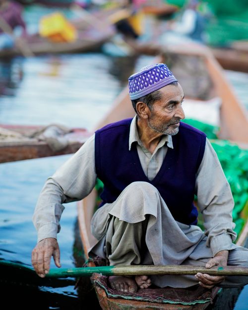 Free Elderly man paddling a traditional wooden boat on a calm waterway. Stock Photo