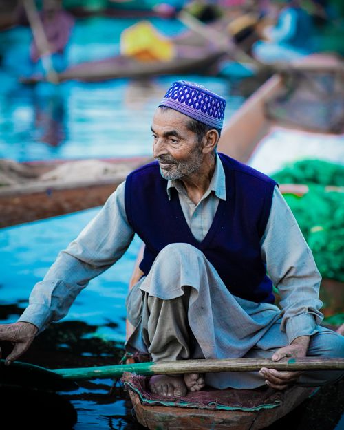 Free Elderly man paddling a traditional boat on a vibrant river, showcasing cultural craftsmanship. Stock Photo