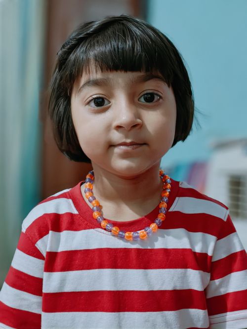 Free Charming portrait of a young girl in a red and white striped shirt, exuding innocence. Stock Photo