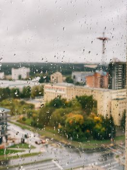 View of a rainy cityscape through a window, showcasing raindrops on glass.