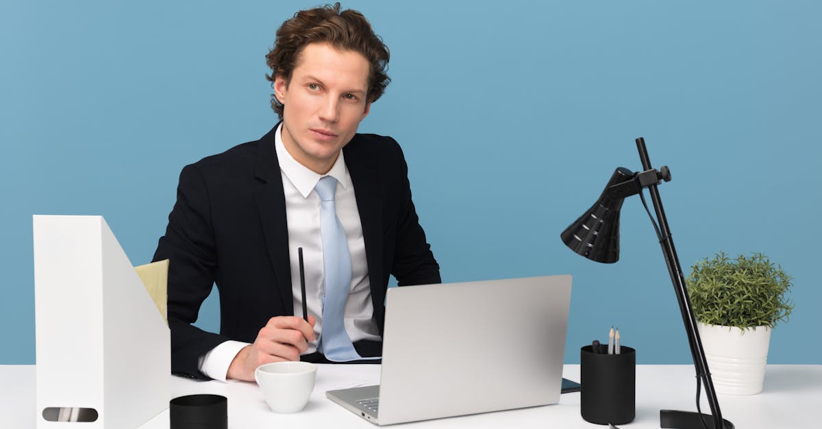 Man Sitting With Laptop Computer on Desk and Lamp